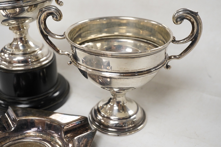 A pair of George V small silver two handled trophy cups by J W Tiptaft & Son Ltd, Birmingham, 1933, height 10cm, one with plinth, together with a George V silver ashtray with inset coin base.